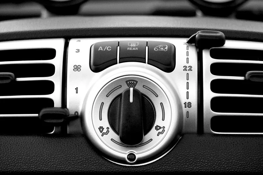 Car dashboard A/C button and temperature dial between two air vents