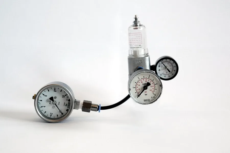 Two dial pressure gauges connected to a small regulator on a white background