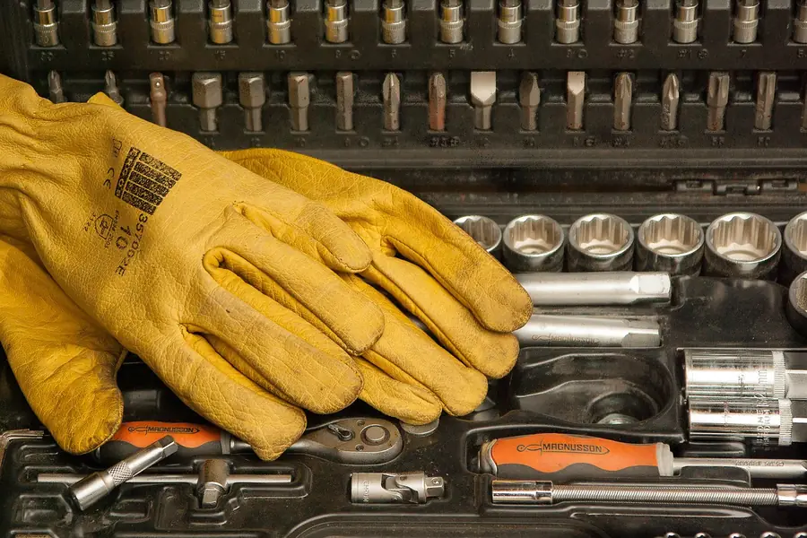 Leather work gloves resting on a socket set in a toolbox