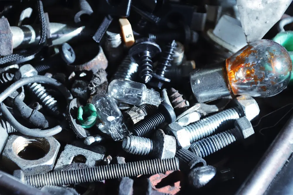 Pile of used nuts, bolts, screws and small light bulbs in a workshop