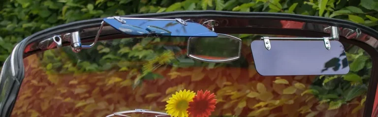 Two sun visors lowered against the windshield header of a classic convertible