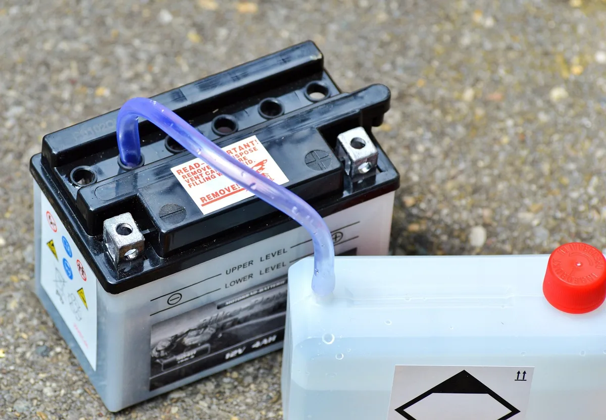 Small 12V lead-acid battery with terminals beside an electrolyte container