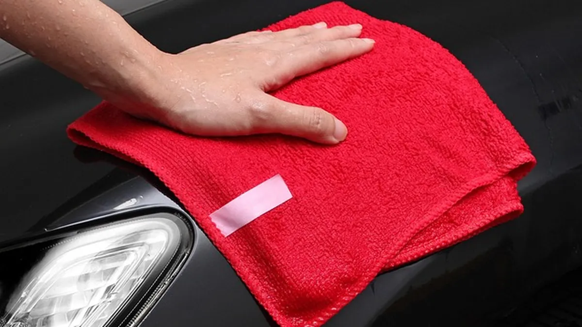 Drying a car by hand with a microfiber towel after a wash to avoid swirl marks