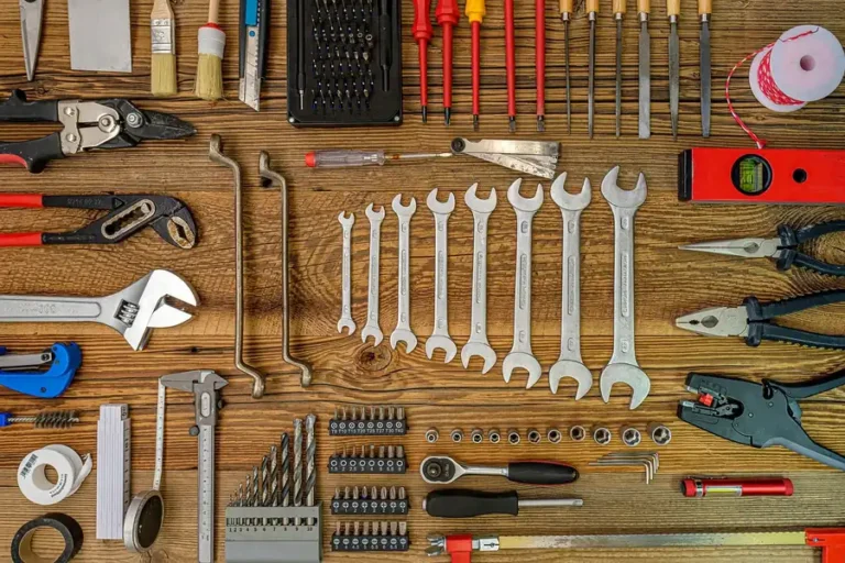 Open-end wrenches, pliers and screwdrivers laid out on a wooden workbench