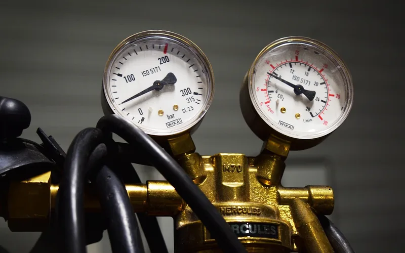 Mechanic reading a pressure gauge and regulator in a repair shop