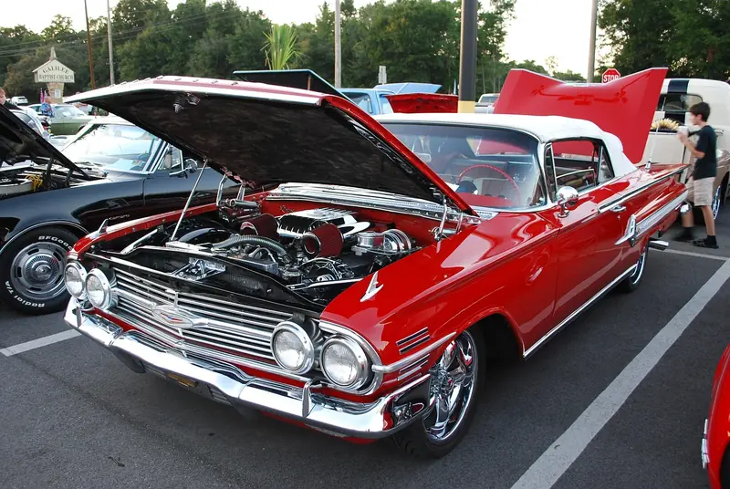 Red classic convertible with the hood open showing the engine bay