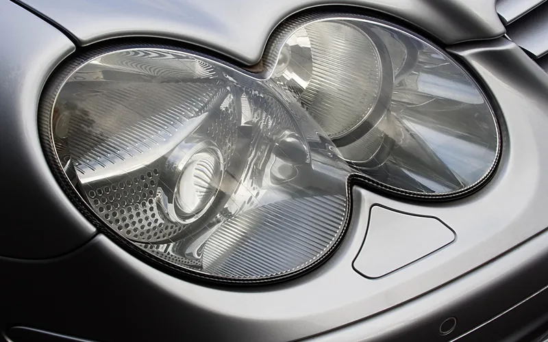 Close-up of a silver car headlight lens with a ribbed reflector behind it