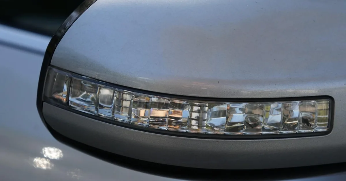 Close-up of the silver painted housing of a car side mirror with a turn signal