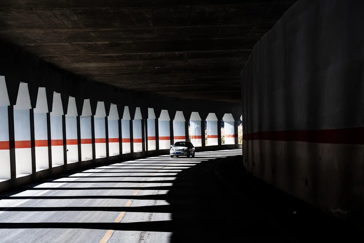A single car driving through a curved road tunnel
