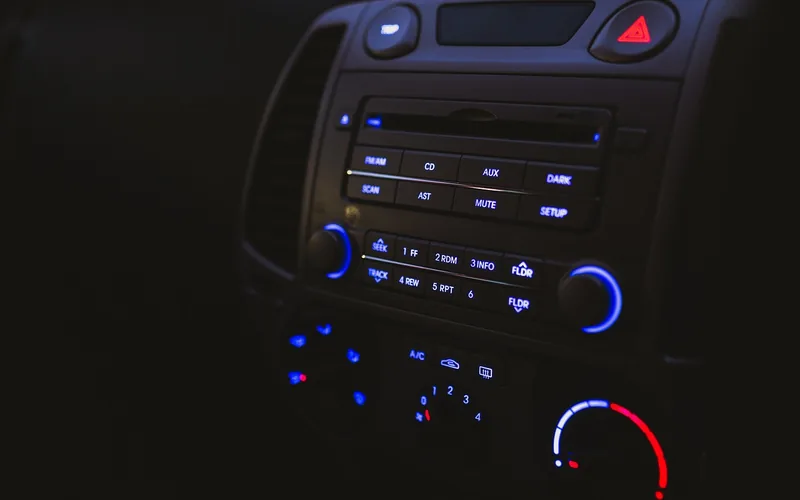 A car radio and climate controls with backlit buttons at night
