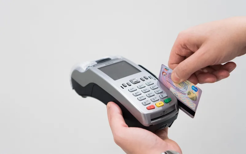 Hand holding a bank card at a card payment terminal