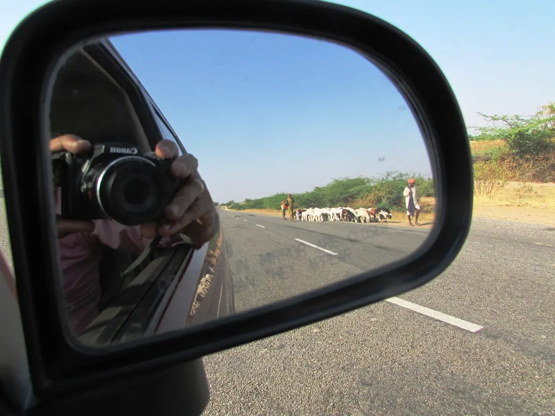 A car side mirror showing the road behind the vehicle