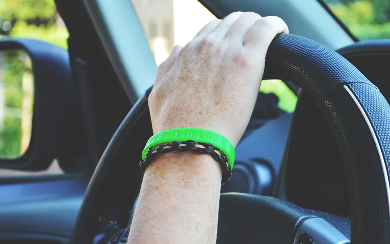 Driver's hands on the steering wheel while driving on a road