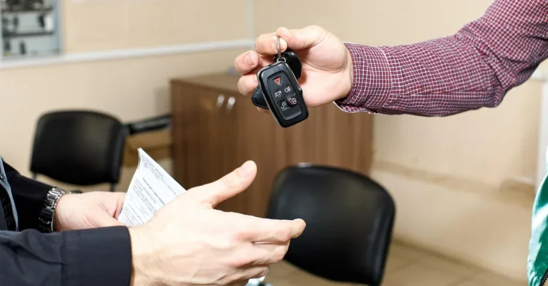 Car keys being handed over beside printed rental paperwork
