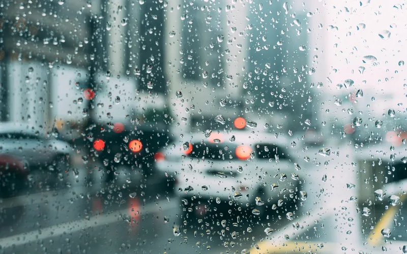 Raindrops on a car window with blurred traffic behind the glass Raindrops on a car window with blurred traffic behind the glass