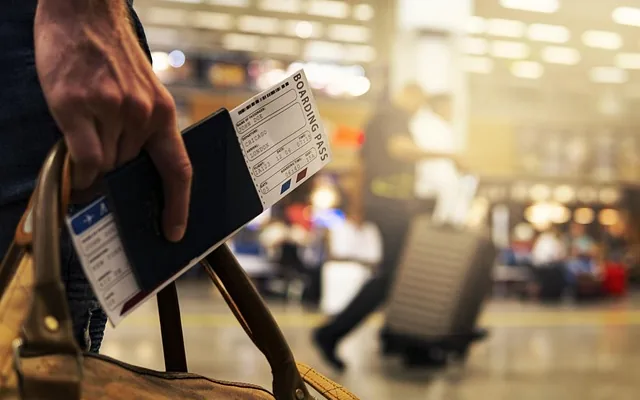 Traveler holding a passport and boarding pass in an airport terminal