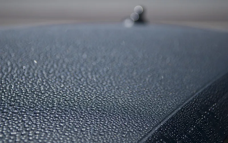 Water beading on a waxed car roof, showing the hydrophobic UV-protective barrier wax creates
