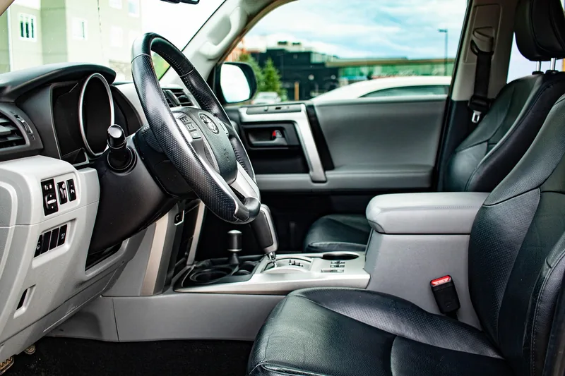 Black leather driver seat beside a plastic door panel and center console