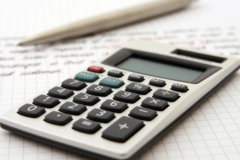 Pocket calculator and pen on paper for working out a car price