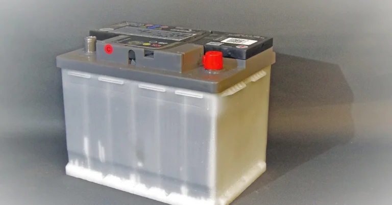 A car battery with a grey case and terminal covers on a grey background