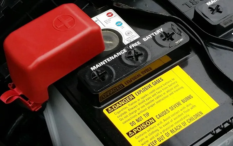 Warning label on a car battery cover about explosive gases and acid
