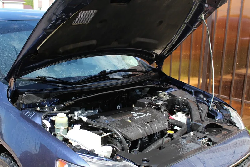 Blue car with its hood propped open showing the engine bay and several fluid reservoirs