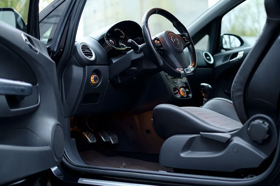 Open driver door showing the front footwell and carpet of a parked car