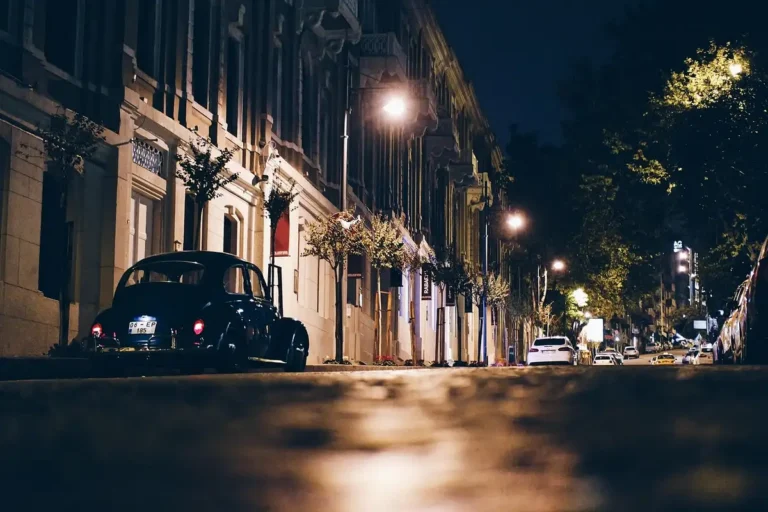 Dark classic car parked on a quiet city street at night