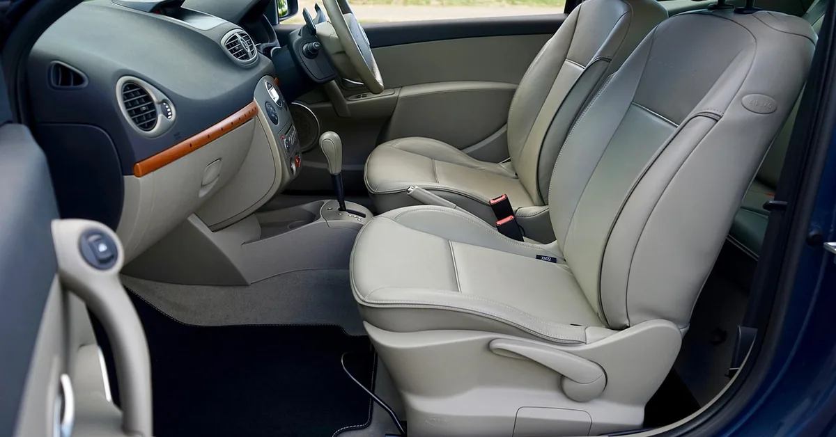 Clean light gray car interior with leather seats and dashboard seen through the open driver door