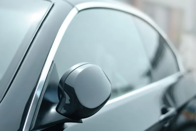 Close-up of the side window and mirror of a dark car