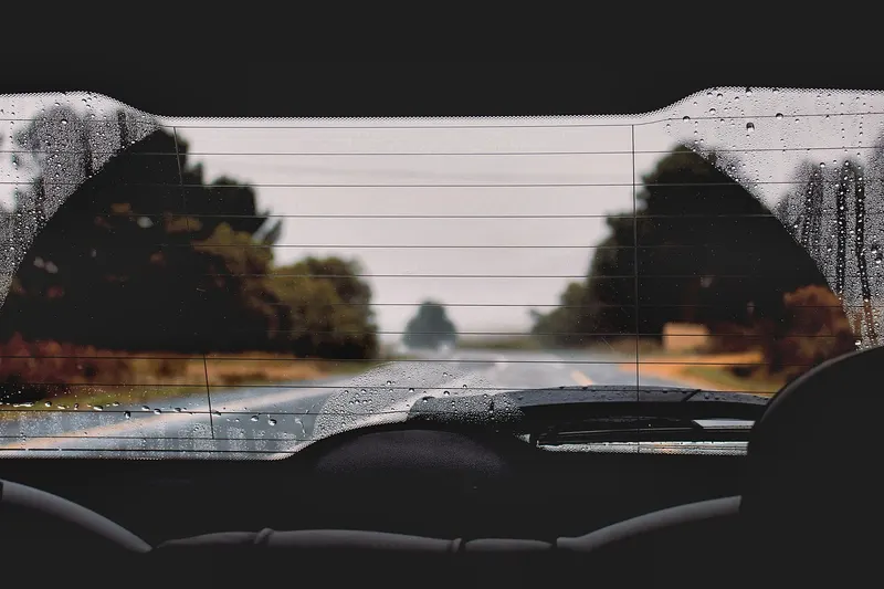 Rear window seen from inside a car with horizontal grid lines and water droplets