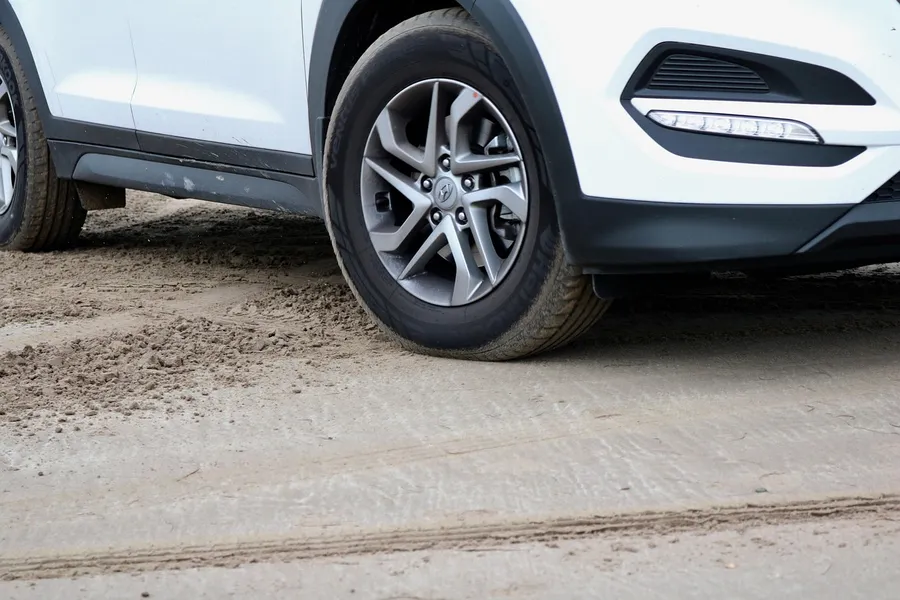 White SUV front wheel and wheel opening with black trim along the arch and lower body