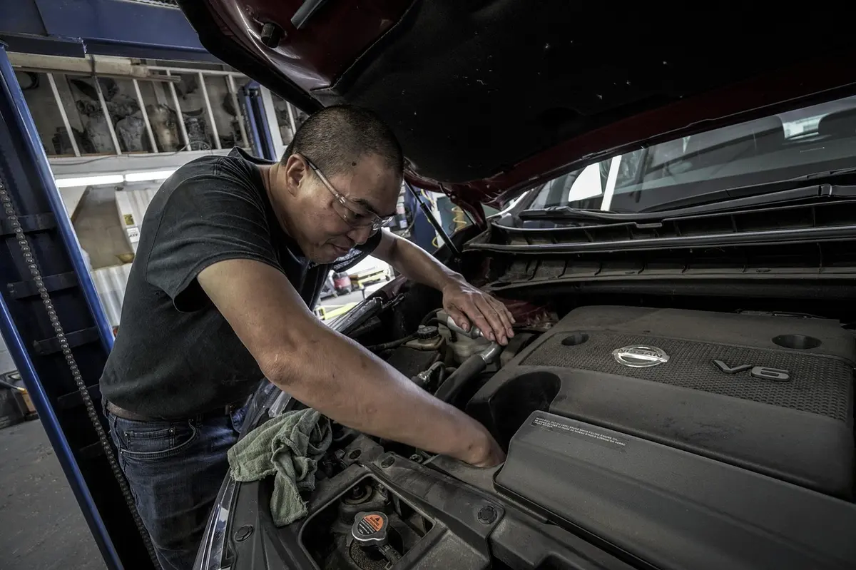 Person wearing safety glasses leaning into an open engine bay
