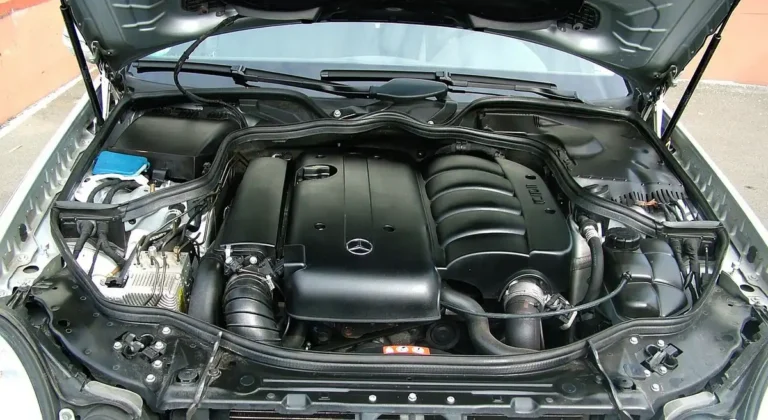 Car with the hood propped open showing the engine bay where the 12V battery work happens