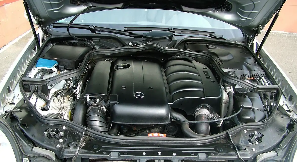 Car with the hood propped open showing the engine bay where the 12V battery work happens