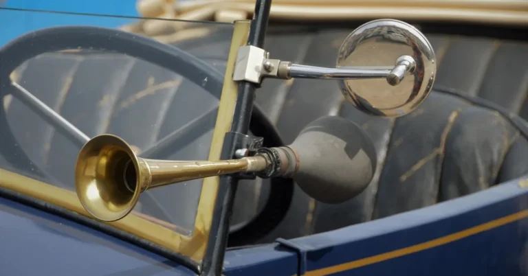 Brass bulb horn mounted beside the windshield of a vintage car