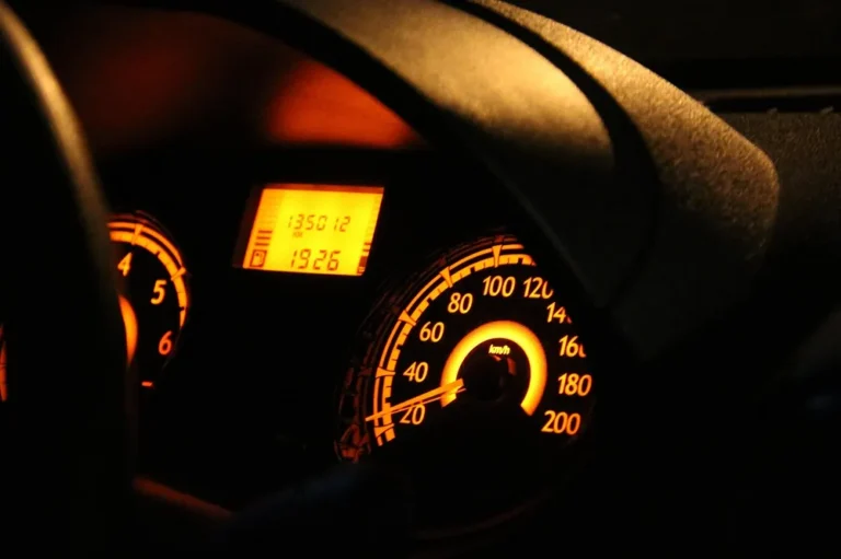 Illuminated car instrument cluster with speedometer and tachometer at night