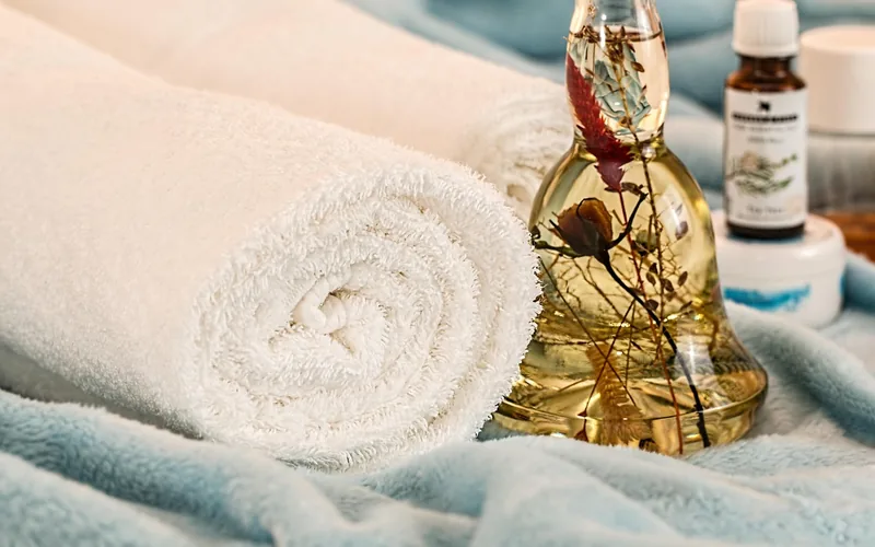 Rolled white towels beside a glass essential oil bottle, evoking a spa-style blend for a relaxing drive Rolled white towels beside a glass essential oil bottle, evoking a spa-style blend for a relaxing drive