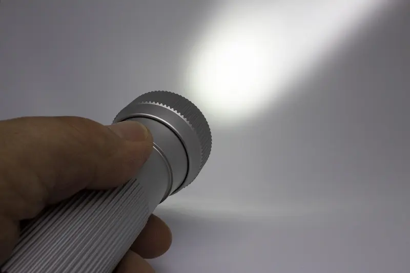 Hand holding a lit flashlight