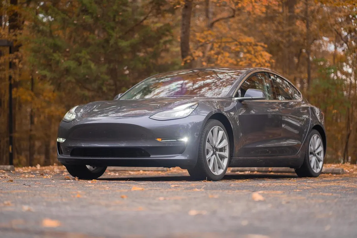 A gray electric sedan seen from the front with a smooth bumper and no front license plate