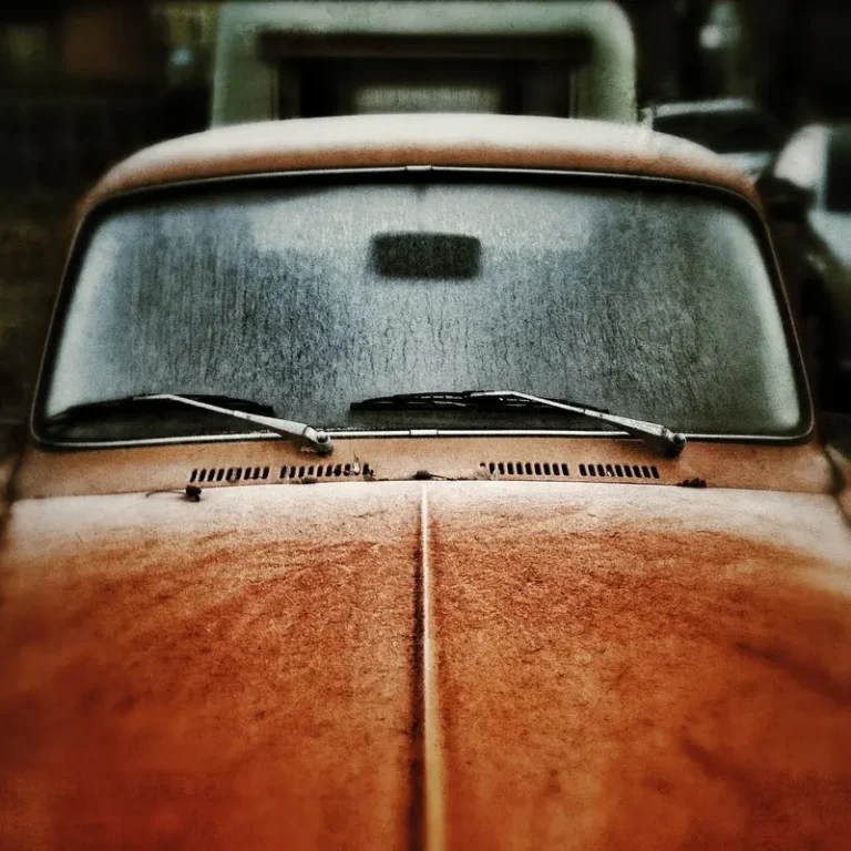 Frosted car windshield and wipers on the hood of an orange vintage car