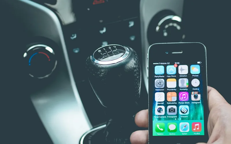 iPhone held inside a car cabin beside the gear shifter iPhone held inside a car cabin beside the gear shifter