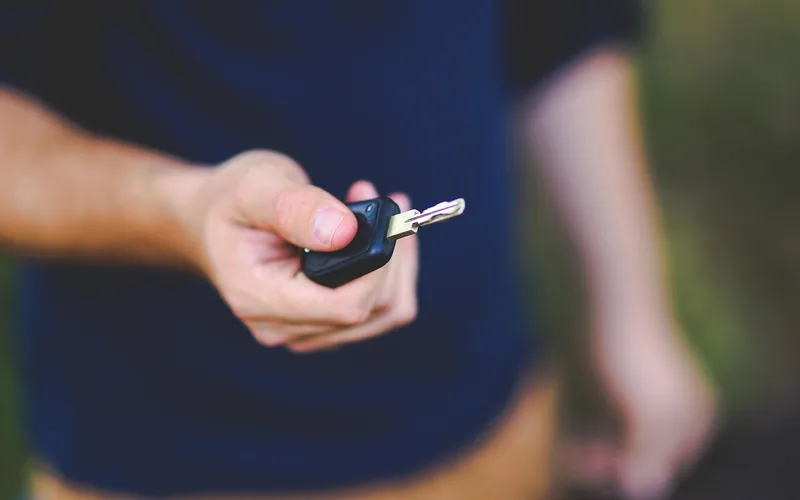 Man holding a black car key fob with remote buttons before getting it copied Man holding a black car key fob with remote buttons before getting it copied