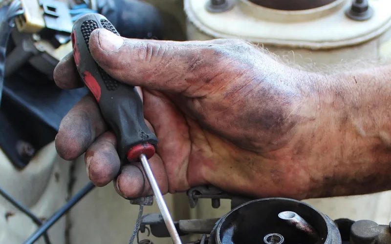 Mechanic's hand using a screwdriver to troubleshoot an engine component