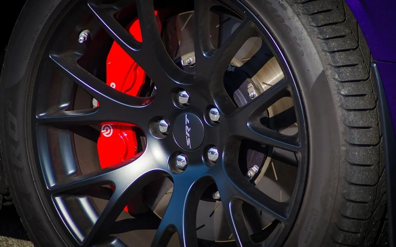 Mechanic inspecting a car's wheel and suspension components for a wobble Mechanic inspecting a car's wheel and suspension components for a wobble