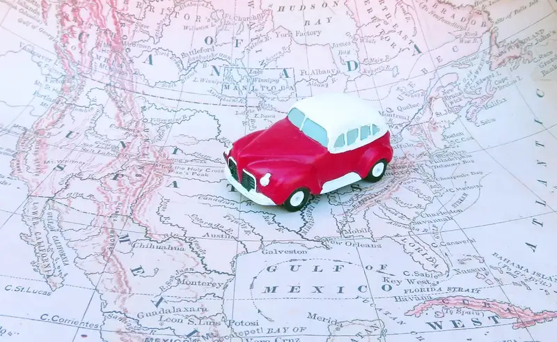 A small red toy car on an old map of North America