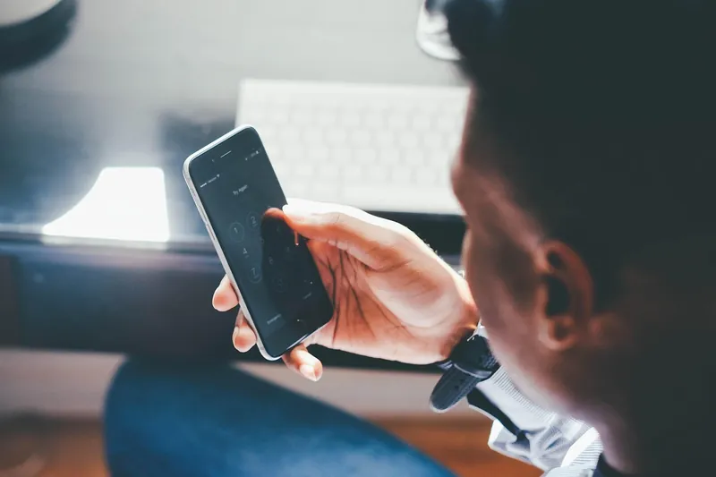 Person holding a smartphone while seated at a desk