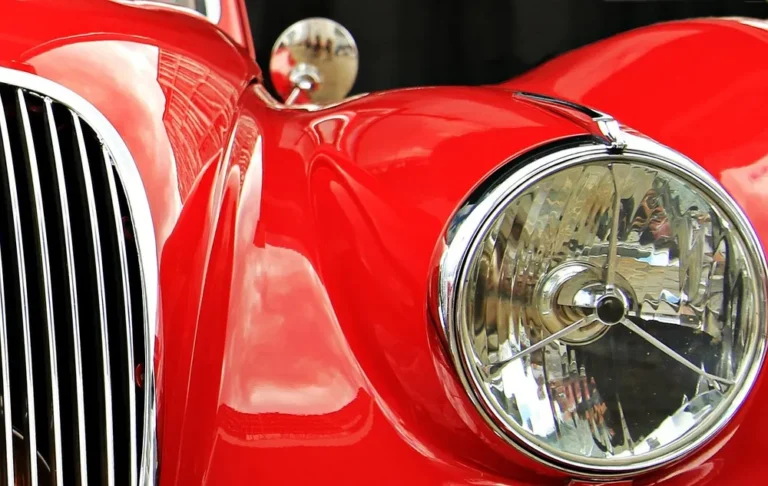 Glossy red paint on the fender and headlight of a classic car