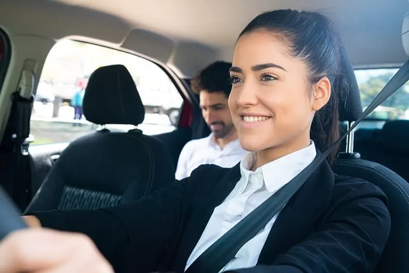 Smiling driver with a passenger in the back seat of a car