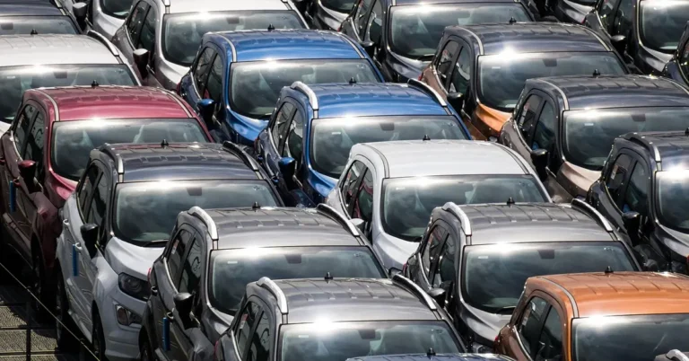 Rows of new cars lined up closely at a vehicle storage lot
